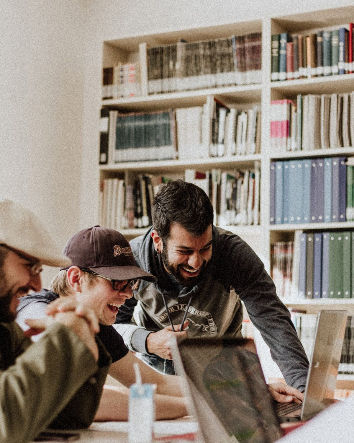 Three people collaborating on laptops in a library
